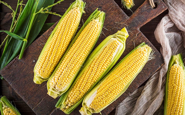11 comidas caseras de América Latina Choclos, un ingrediente de la comida casera de la región, sobre una tabla de madera