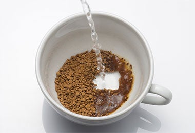 Agua hirviendo vertiéndose sobre taza con yerba mate molida.