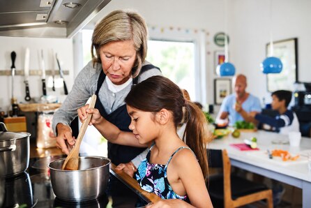 Abuela y nieta cocinando con un cazo.