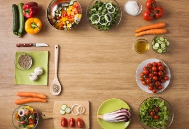 Cocina en casa con verduras frescas y picadas. Cocina en casa con verduras frescas y picadas, ensaladas y utensilios de cocina de madera, vista superior con espacio de copia.