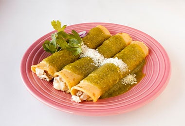 Enchiladas con queso duro blando. Enchiladas con queso duro blando y queso sobre un plato.