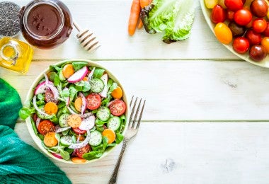 Ensalada con encurtidos. Tazón de ensalada mixta fotografiado desde arriba sobre una mesa de picnic verde claro.