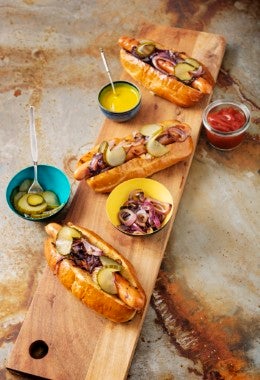 hotdogs con pepinillos Vista de ángulo alto de una selección de 3 hot-dogs artesanales en panecillos de brioche con pepinillos.