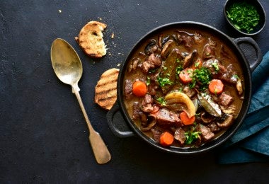 Guiso de carne con verduras y champiñones al vino tinto en sartén.