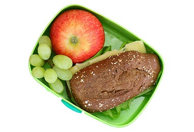 Sándwich de jamón y lechuga, manzana y uvas, tres comidas para viaje.