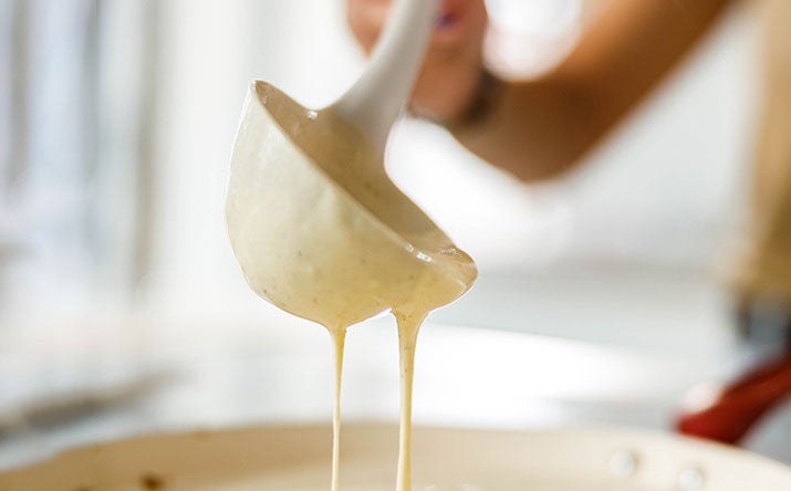 Una mujer preparando pancakes con un cucharón