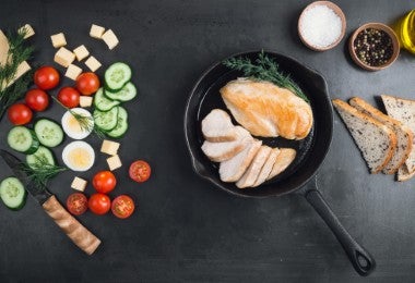 Pechuga de pollo frita en sartén de hierro fundido con verduras frescas en rodajas. Grupos alimenticios.