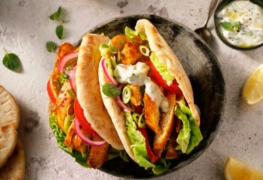 Gyro de pollo estilo griego con lechuga, tomate, cebolla y salsa tzatziki