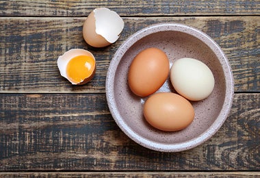 Tres huevos enteros y un huevo con una yema en su cáscara para preparar salsa holandesa