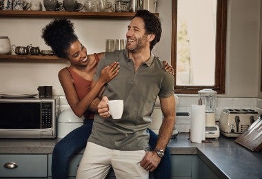 Una pareja riendo en su cocina con microondas.