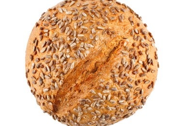 Una hogaza de delicioso pan casero con salvado de trigo aisladas sobre fondo blanco.