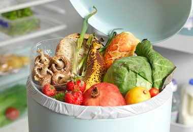 Residuos frescos de vegetales y frutas en un bote de basura orgánica.