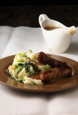 Salchichas y pure de papa con salsa.