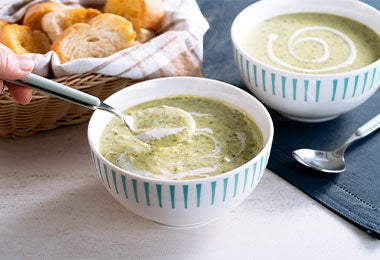 Tazones llenos de sopa de chayote junto a canasta de pan.