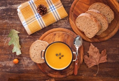 Sopa de calabaza caliente en un plato sobre una mesa rústica, primer plano.