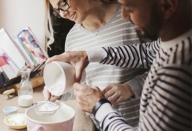 Pareja tamizando harina en una mini zaranda para cocina.