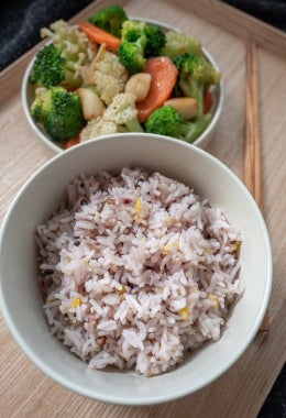 Un saludable tazón de arroz integral y diferentes tipos de granos con un plato de brócoli, coliflor y zanahoria. También apto para vegetarianos.