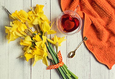 Taza de té de caléndula junto a ramo de caléndulas.