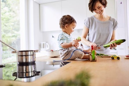 Madre cocinando verduras con un cazo.