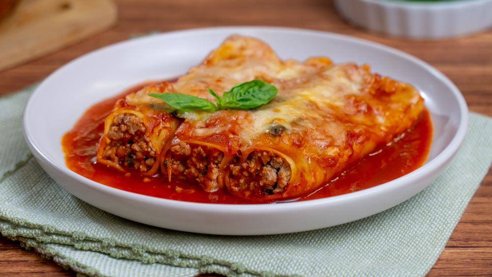 Canelones rellenos de carne molida al horno con salsa roja y queso gratinado