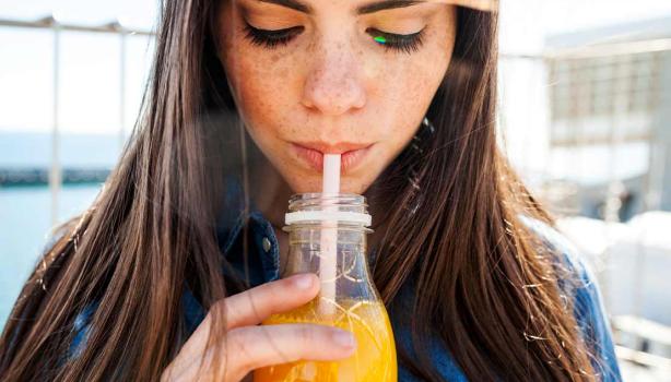 Mujer bebiendo un refrescante jugo de zanahoria con limón
