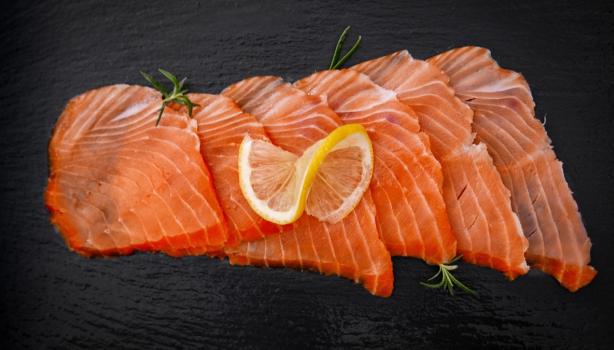 Pequeños trozos de salmón ahumado frío sobre fondo negro.