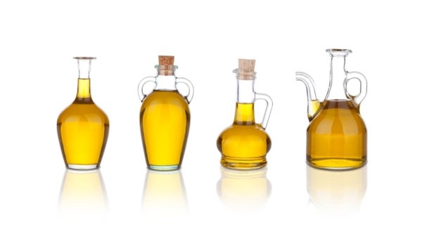 Cuatro tipos de aceite de cocina en recipientes de vidrios distintos.