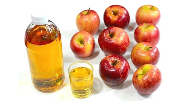 Vinagre de sidra de manzana al lado de manzanas.