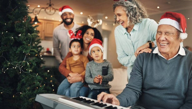 Navidad: una familia feliz y un anciano al piano en el salón, celebrando con canciones de navidad.