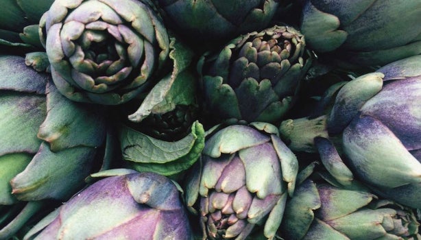 Alcachofas frescas verdes y moradas en primer plano, perfectas para conocer mejor para qué sirve la alcachofa en recetas