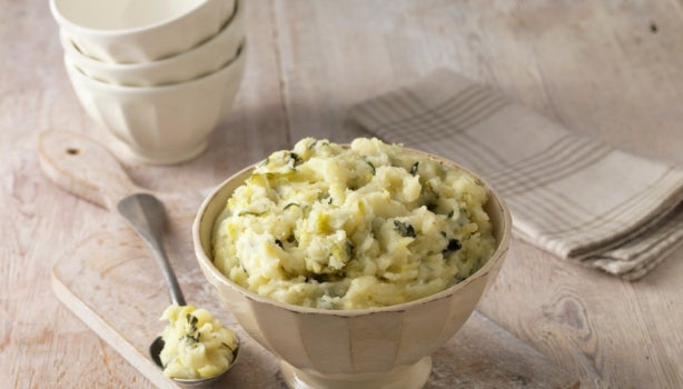 Puré de papa en un recipiente facetado color crema con cuchara de metal.