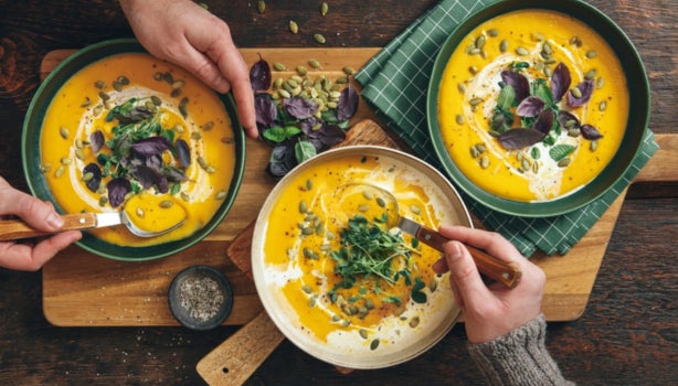 Sopa cremosa de calabaza asada vegana sobre fondo de madera.