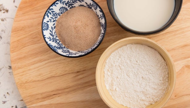 Almidón de yuca, harina y leche. Cuenco decorativo de bambú y negro. Plato giratorio de madera. Vista superior.