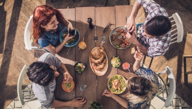 Vista superior de jóvenes disfrutando de un almuerzo con todos los grupos alimenticios en un restaurante.