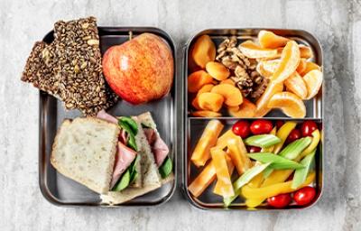 Comida para viaje: barras de cereal, sándwich, frutas, verduras picadas y frutos secos. 