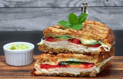 Pan panini relleno de jamón, tomate y albahaca, acompañado con salsa Pan panini relleno de jamón, tomate y albahaca, acompañado con salsa