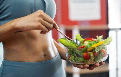 Una mujer con una ensalada después de salir a hacer ejercicio en una rutina de vida activa