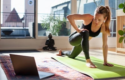 Mujer estirando en casa y haciendo ejercicios de cardio para principiantes