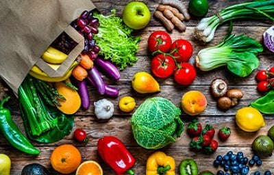 Múltiples frutas y verduras regadas sobre una mesa, que son alimentos que aportan vitaminas esenciales
