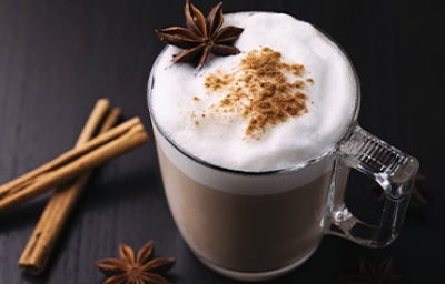 Bebida caliente con leche, canela y anís en una taza de vidrio grueso en una toma en picado