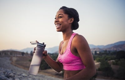 Mujer haciendo deporte e hidratándose con botella reutilizable