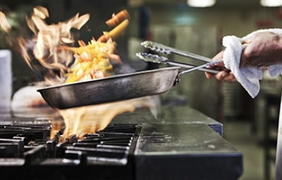 Persona salteando verduras con las precauciones necesarias para evitar quemaduras por aceite
