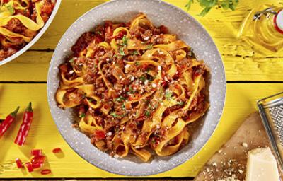 Pasta a la boloñesa con carne, queso parmesano y hierbas aromáticas sobre un fondo amarillo