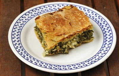 Una porción de la receta griega spanakopita sobre un plato blanco y azul.