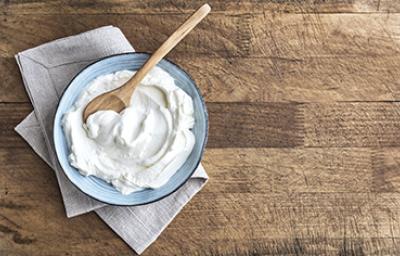 Un plato con yogurt casero recién preparado y una cucharita de madera
