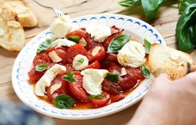Ensalada caprese con tomate, queso, albahaca y pan en un plato