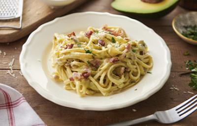 Pasta carbonara con pollo, tocino y hierbas en un plato hondo