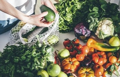 Una persona sacando productos orgánicos, frutas y verduras de una bolsa