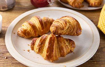 Croissant de almendra fresco Tres deliciosos croissants de almendras frescos sobre un plato