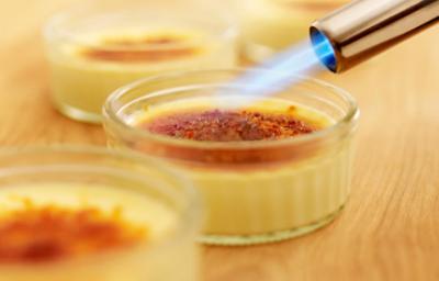 Soplete de cocina en acción Soplete de cocina caramelizando la superficie de un flan